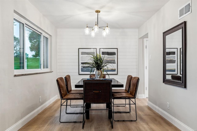 dining room with baseboards, a notable chandelier, visible vents, and wood finished floors