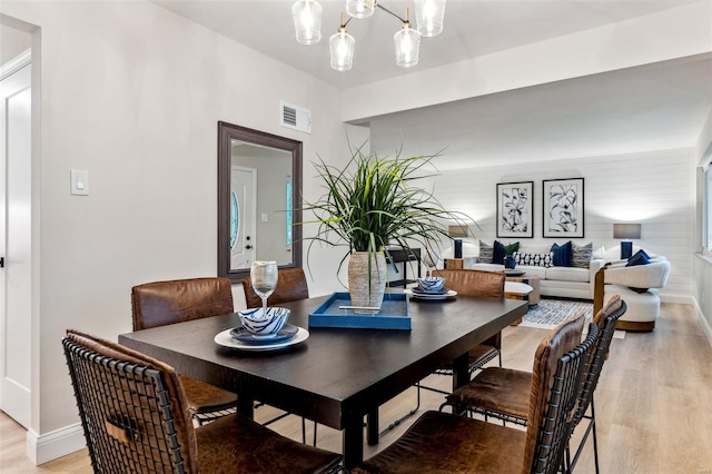 dining area with a notable chandelier, baseboards, visible vents, and light wood-style flooring