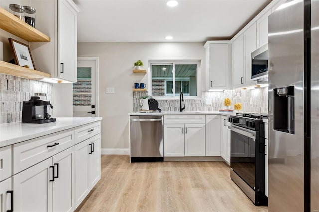 kitchen with appliances with stainless steel finishes, tasteful backsplash, open shelves, a sink, and white cabinets