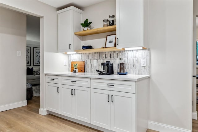 bar featuring light wood-style floors, baseboards, and decorative backsplash