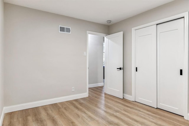 unfurnished bedroom with light wood-style floors, baseboards, a closet, and visible vents