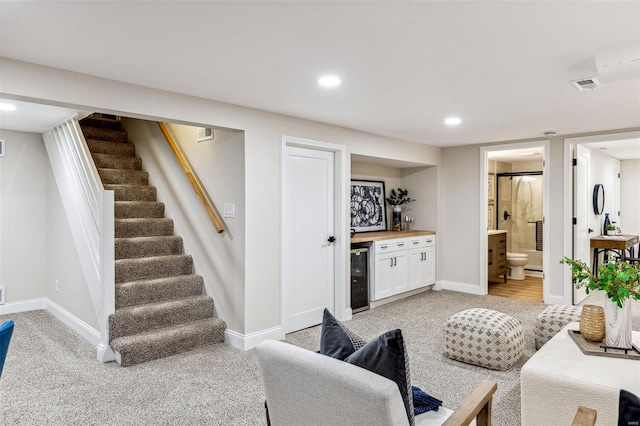 living area with stairs, wine cooler, light carpet, and indoor bar