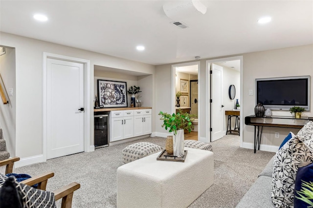 living area featuring light carpet, beverage cooler, wet bar, baseboards, and visible vents
