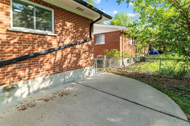 view of side of property with brick siding, fence, and a patio