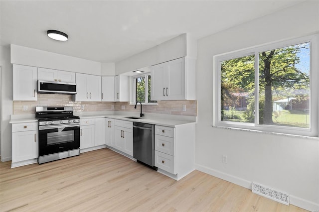 kitchen featuring appliances with stainless steel finishes, decorative backsplash, a sink, and visible vents