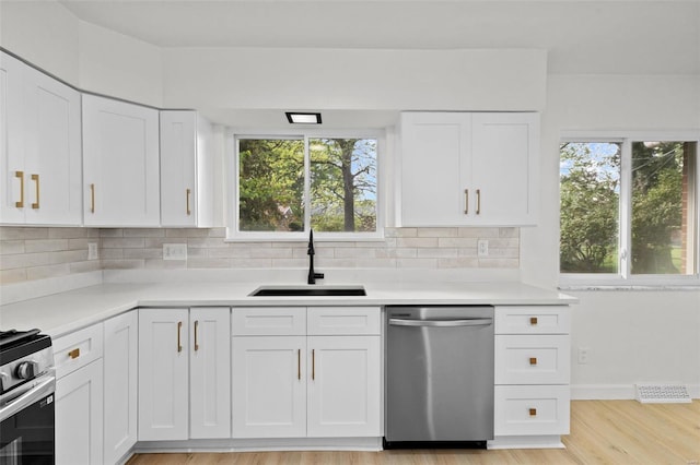 kitchen featuring light countertops, appliances with stainless steel finishes, decorative backsplash, and a sink