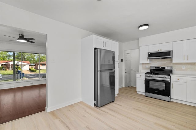 kitchen with decorative backsplash, light wood finished floors, appliances with stainless steel finishes, and white cabinets