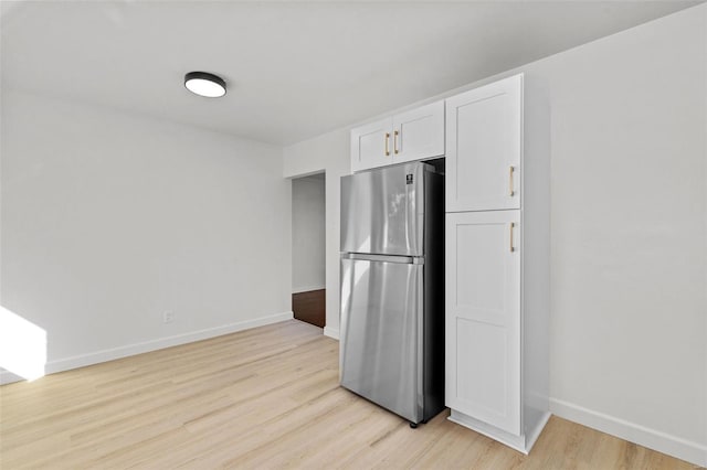 kitchen with baseboards, freestanding refrigerator, light wood-style flooring, and white cabinetry