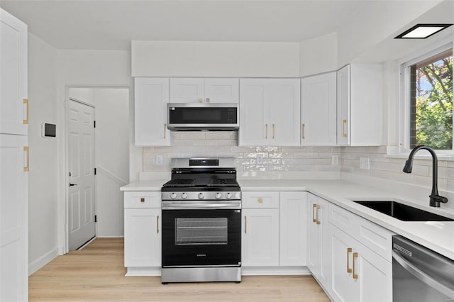 kitchen featuring a sink, light countertops, stainless steel appliances, and white cabinetry