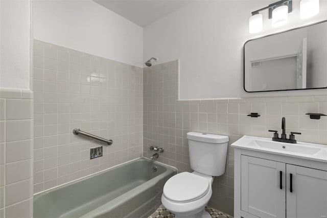 full bath featuring wainscoting, washtub / shower combination, vanity, toilet, and tile walls