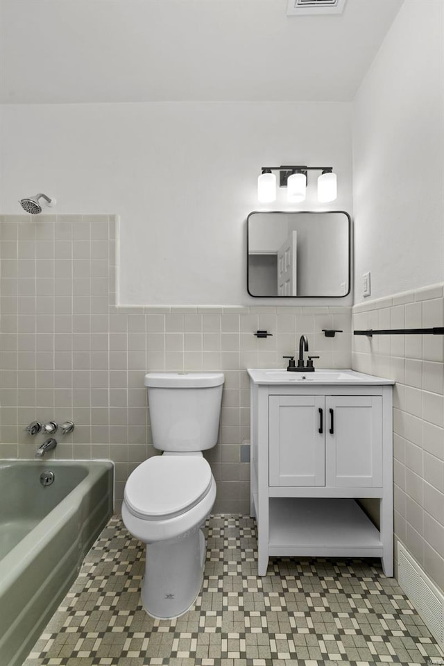 full bath with toilet, tile walls, a wainscoted wall, and vanity