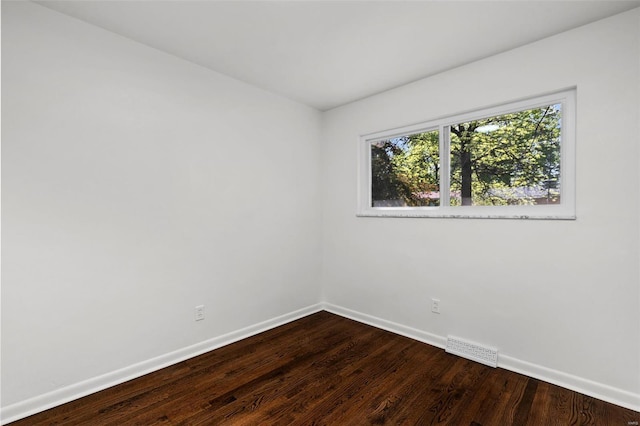 spare room with baseboards, dark wood-style floors, and visible vents