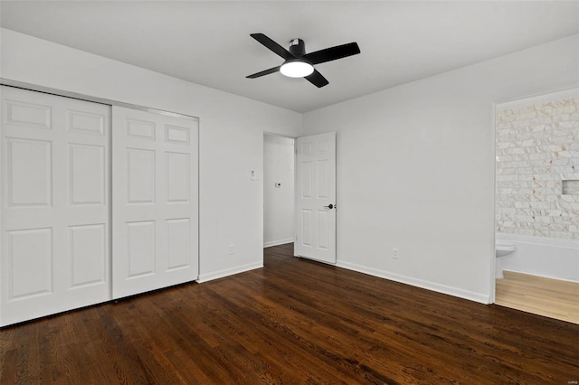 unfurnished bedroom featuring a closet, baseboards, ensuite bath, and dark wood-style floors
