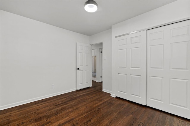 unfurnished bedroom featuring baseboards, a closet, and dark wood-style flooring
