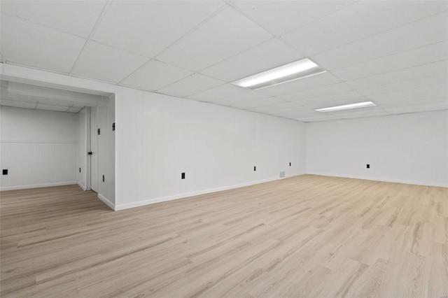 finished below grade area featuring light wood-style floors, baseboards, and a drop ceiling