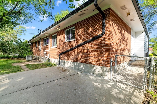 view of side of home with brick siding, fence, and a patio