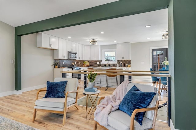 kitchen with baseboards, appliances with stainless steel finishes, white cabinets, and tasteful backsplash