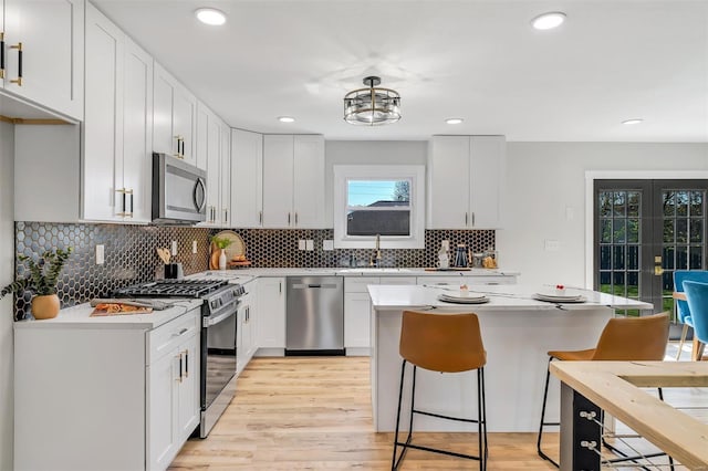 kitchen with light countertops, a breakfast bar, stainless steel appliances, and light wood-type flooring