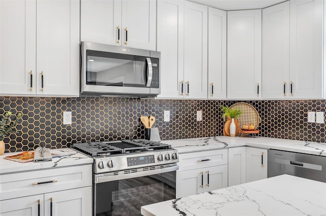 kitchen featuring tasteful backsplash, light stone countertops, stainless steel appliances, and white cabinetry