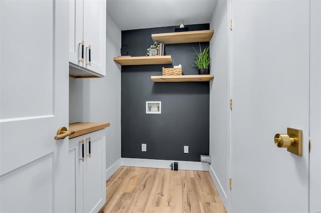 laundry room with light wood-type flooring, hookup for a washing machine, baseboards, and cabinet space