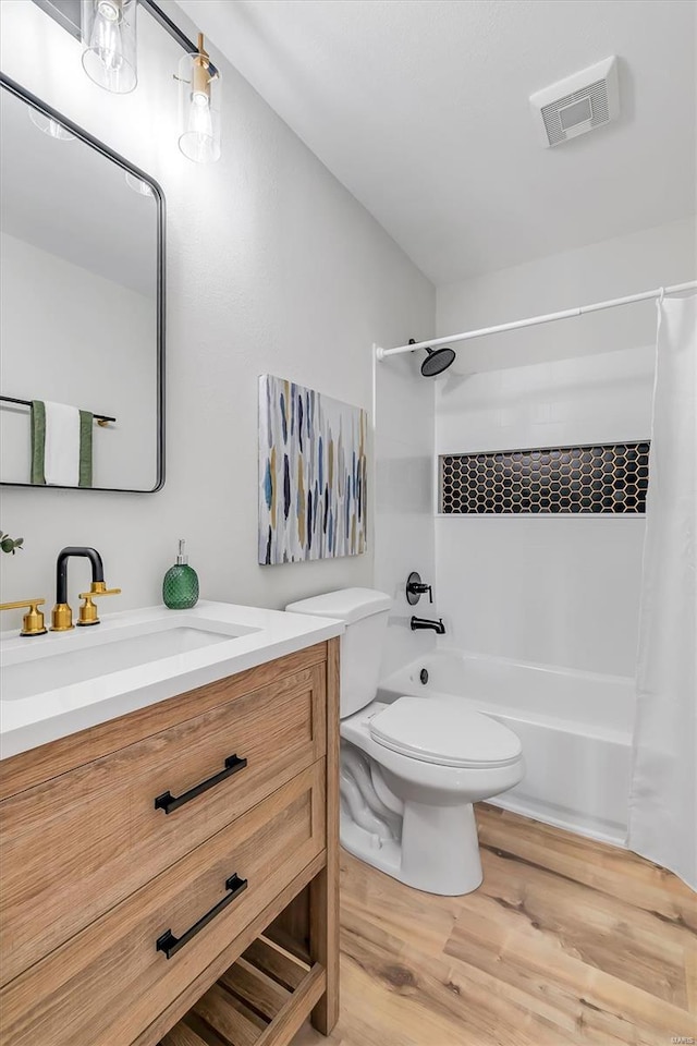 bathroom featuring visible vents, wood finished floors, shower / tub combo, vanity, and toilet