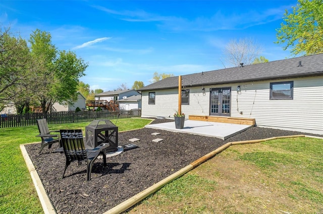 rear view of property featuring fence private yard, a patio, french doors, a lawn, and an outdoor fire pit