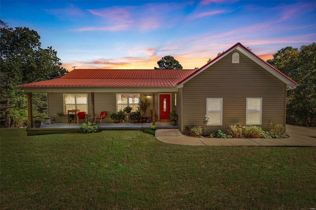 ranch-style house featuring covered porch, metal roof, and a front lawn
