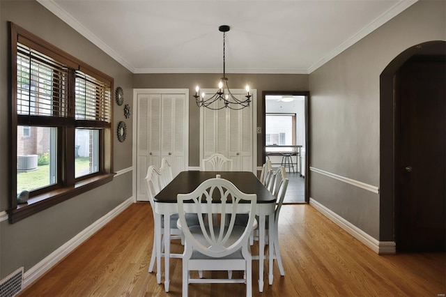 dining room featuring visible vents, arched walkways, a notable chandelier, and light wood-type flooring