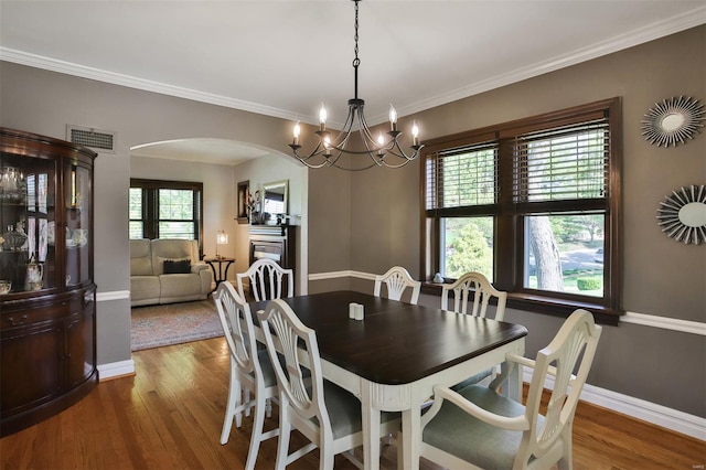 dining room featuring an inviting chandelier, arched walkways, wood finished floors, and visible vents