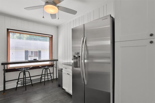 kitchen featuring ceiling fan, crown molding, stainless steel fridge with ice dispenser, baseboards, and white cabinetry