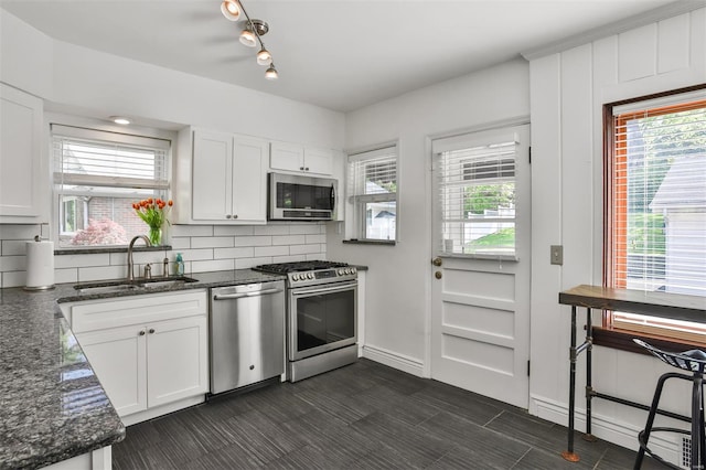 kitchen featuring white cabinetry, appliances with stainless steel finishes, a sink, and tasteful backsplash