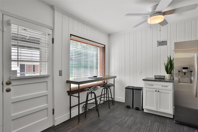 kitchen featuring a ceiling fan, visible vents, baseboards, stainless steel fridge, and dark stone counters