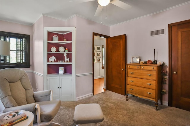 living area with a ceiling fan, visible vents, crown molding, baseboards, and carpet