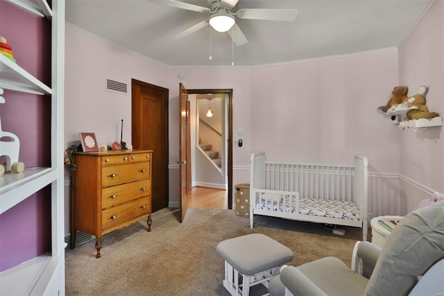 carpeted bedroom with a ceiling fan, visible vents, and ornamental molding