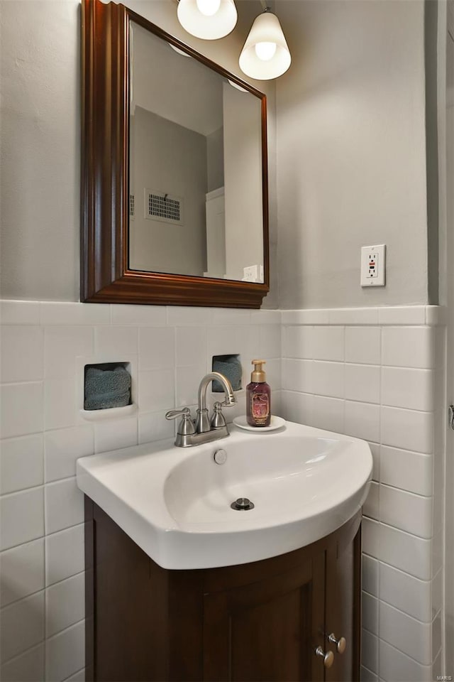 bathroom with visible vents, a wainscoted wall, vanity, and tile walls