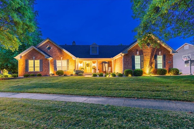 ranch-style home featuring a chimney, brick siding, and a front yard
