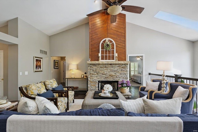 living room with high vaulted ceiling, ceiling fan, a stone fireplace, and visible vents
