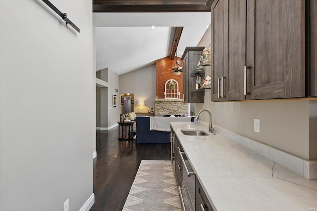 kitchen with dark brown cabinets, light stone countertops, a sink, baseboards, and dark wood-type flooring
