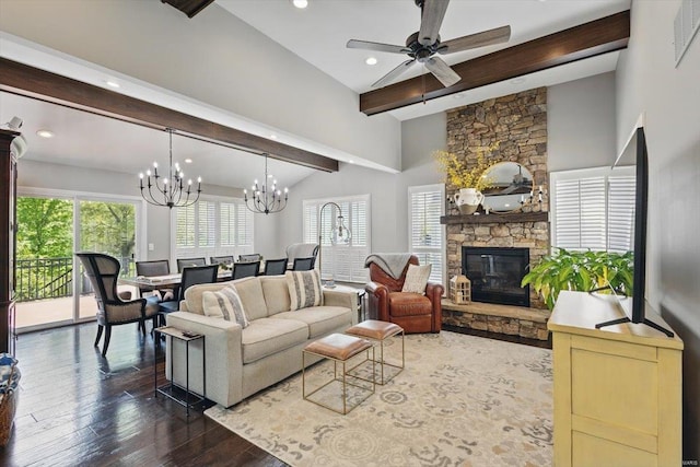 living area with wood-type flooring, a stone fireplace, a healthy amount of sunlight, and ceiling fan with notable chandelier