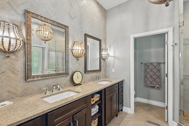 bathroom with baseboards, a sink, a chandelier, and double vanity