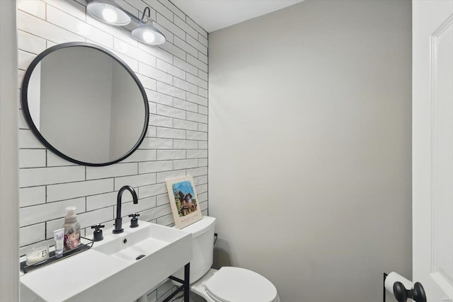 half bathroom featuring backsplash, toilet, tile walls, and a sink