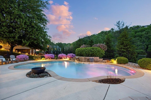 pool at dusk featuring a patio, fence, and a fenced in pool