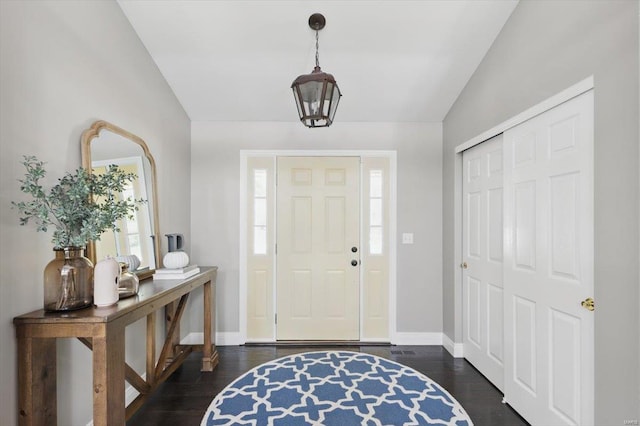 foyer with baseboards, lofted ceiling, and dark wood-type flooring