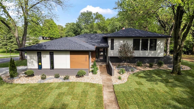 tri-level home featuring a shingled roof and a front lawn