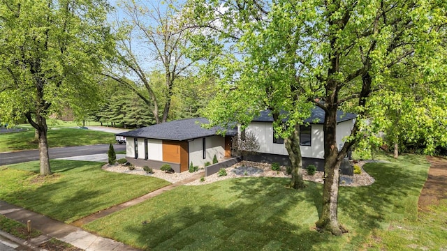 view of front of house featuring stucco siding, roof with shingles, and a front lawn