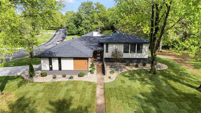 view of front of house with a front lawn and roof with shingles