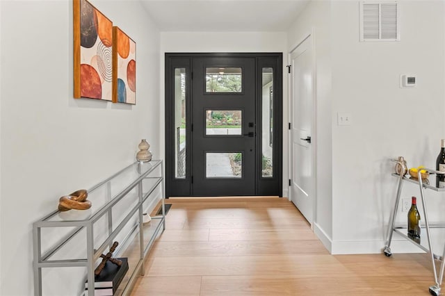 foyer entrance featuring visible vents, baseboards, and light wood-type flooring