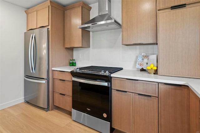 kitchen with light wood-style floors, light countertops, wall chimney exhaust hood, and appliances with stainless steel finishes