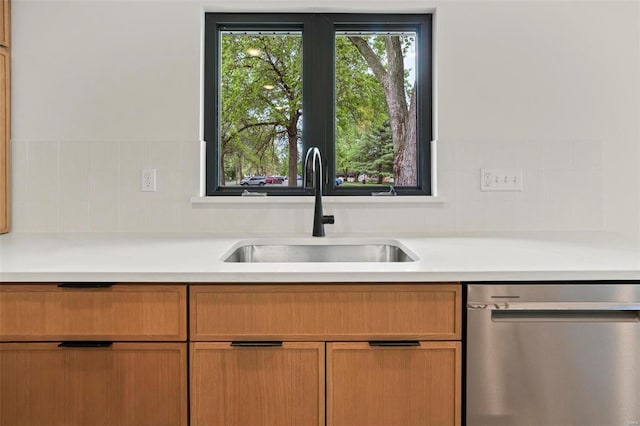 kitchen with a sink, light countertops, tasteful backsplash, and dishwasher