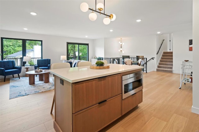 kitchen with stainless steel microwave, a wealth of natural light, and light wood-style flooring